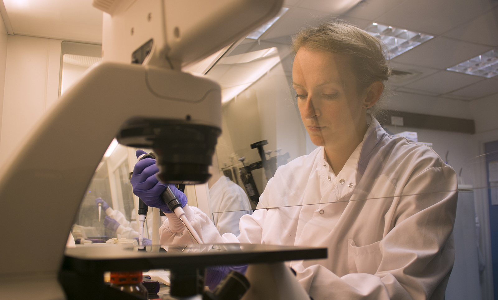 Researcher using a micropipette in a laboratory.